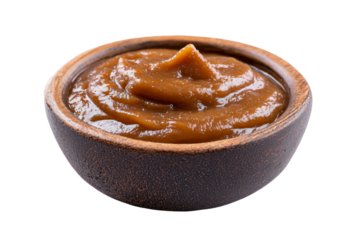 A small rustic wooden bowl filled with sweet creamy caramel sauce.