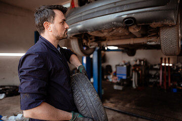 Mechanic changing tire in auto repair shop during daytime work hours