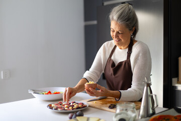 Senior woman preparing healthy fig and cheese appetizer