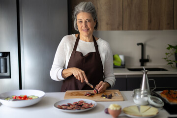 Smiling senior woman preparing healthy food in kitchen