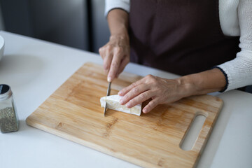 Woman's hands slicing goat cheese on cutting board