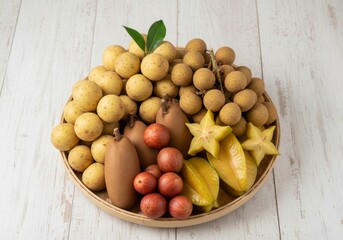 Thai tropical fruit basket with longan, langsat, starfruit, sapodilla, and mafai—colorful, fresh, and naturally arranged on a white surface