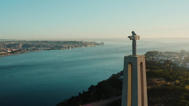 Aerial view of the towering Cristo Rei statue standing tall against the backdrop of the Tagus River and Lisbon's cityscape, Almada, Portugal.