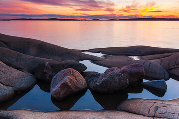 Scenic coastal sunset at rocky shore near gothenburg, sweden featuring calm water and colorful sky reflecting in tide pools