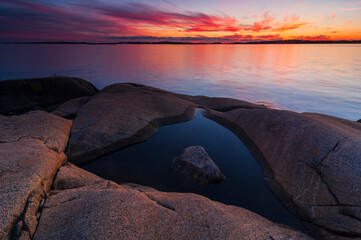 Sunset view over coastal rocks with calm water outside Gothenburg, Sweden