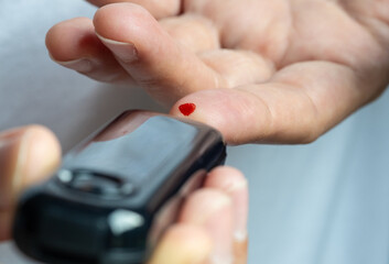 Woman's hands checking diabetes and hyperglycemia with digital blood sugar meter. Healthcare and...