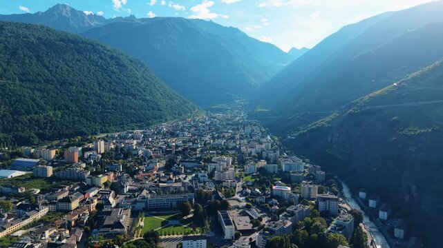 Aerial view of Martigny nestled between lush green mountains and the Rhone river, a serene blend of urban and natural beauty, Martigny, Valais, Switzerland.