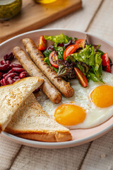 Portion of classic english breakfast with fried eggs, sausages and beans