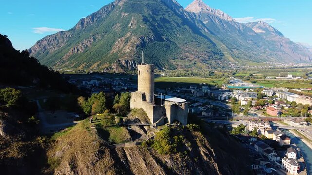 Aerial view of Chateau de la Batiaz atop a hill with mountains in the background, bathed in sunlight, Martigny, Valais, Switzerland.