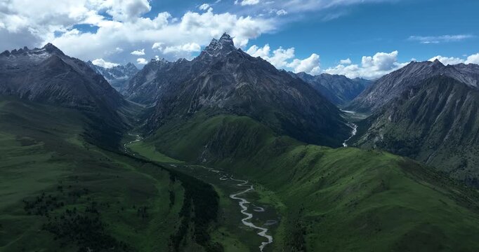 Aerial footage of beautiful high altitude snow capped mountains and forest grassland landscape in China
