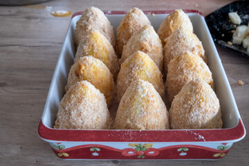 Specialties of Sicilian cuisine called "arancini", filled with rice and meat sauce, ready to be fried
