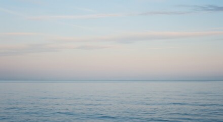 The quiet expanse of the ocean under a gentle pastel-colored sky during a calm twilight hour