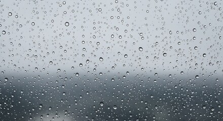 Rainy window with water droplets creating a moody and serene atmosphere against a grey sky