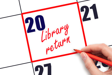 20 th day of the month. Hand writing Library return reminder and drawing red frame on calendar with...