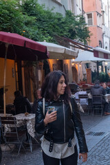 Beautiful woman with long black hair walking through the streets of the historic center of Bolzano in Northern Italy. The woman is thirty-eight years old and wears a black leather jacket