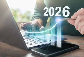 Businessman using laptop with virtual screen showing 2026 and growing graph, concept for digital business growth and investment