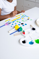 Child painting with sponges and brushes on white table