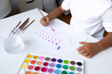 Young child painting with watercolors at home art station