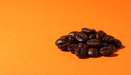 Obraz premium 焙煎によって艶を増した深煎りコーヒー豆がオレンジ背景に包まれた温かな印象