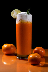 A fresh orange smoothie standing on orange table