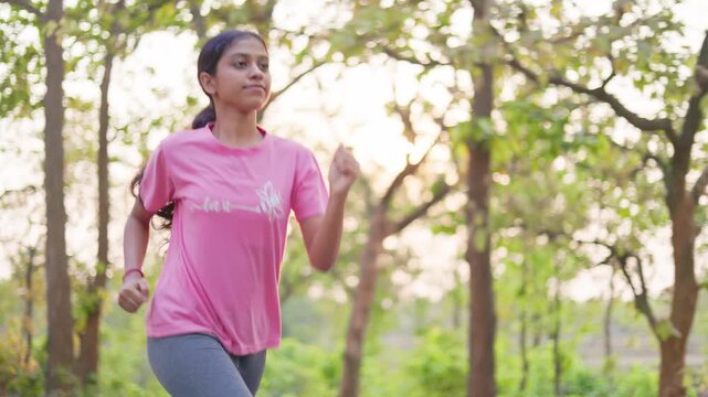 Fit young woman doing warm up exercises in nature during sunrise, maintaining healthy lifestyle.