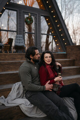 Couple enjoys cozy moments on steps of a modern cabin during winter evening