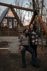 Couple enjoys a cozy moment on a swing in a rustic outdoor setting at dusk