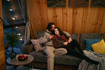 Cozy evening by the fireplace with a couple relaxing together in a wooden cabin