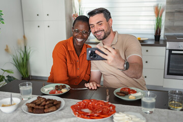 Interracial couple taking a selfie while having lunch in the kitchen