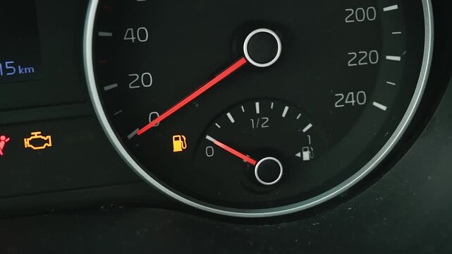 Empty fuel tank warning light glows on modern car dashboard, indicating critical low gas level and urgent need for refueling.