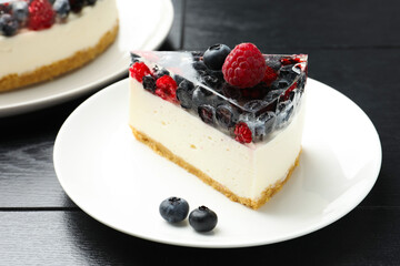 Piece of delicious cheesecake with berries on black wooden table, closeup