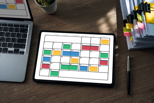 showing a monthly calendar with color coded time blocking on a wooden desk, ideal for planning schedules, appointments, projects, and home office productivity.
