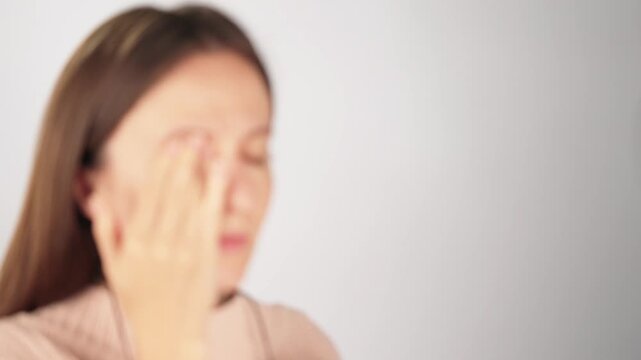 Soft focus shot of an unrecognizable woman removing her eyeglasses and rubbing tired eyes. Concept of blurred vision, eye strain and need for correction. Copy space for text or branding.