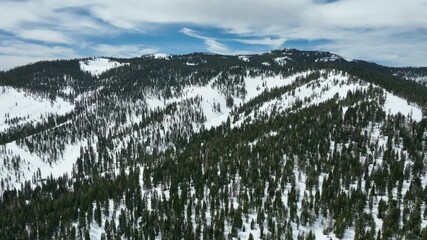 Aerial view backwards in front of snowy mountain of Tahoe, winter day in USA
