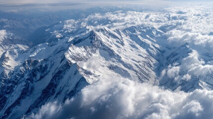 Aerial view of snow-capped mountains and fluffy clouds in the sky.