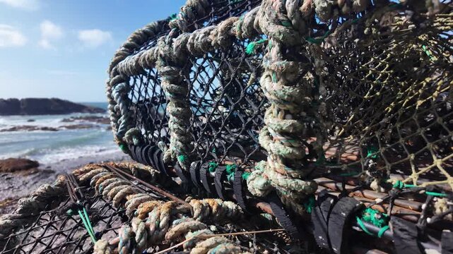 Old crab traps resting on the rugged Isle of Man coastline under a blue sky. close up, push forward
