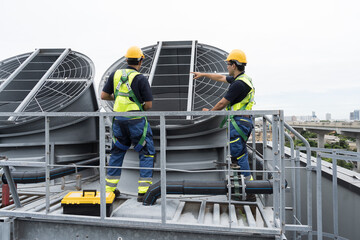 Industry HVAC system. Cooling tower on rooftop. Asian male engineer or technician maintenance and repair of cooling tower on rooftop of building, using handyman tools