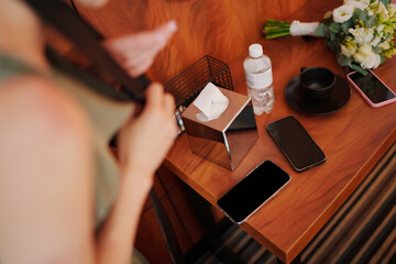 Items on a wooden table with a person adjusting their hair in a room