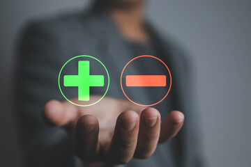 Businessman holding virtual plus and minus icons, concept of decision making, financial management,...