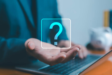 Businessman holding virtual question mark icon above laptop, concept of problem solving, decision...