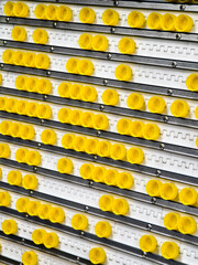 Colorful yellow bottle caps arranged neatly on a display wall in a beverage production facility