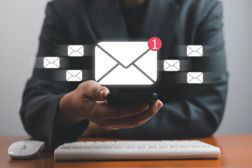 Businessman using smartphone with digital email icons and new message notification, concept of online communication, email marketing, and business technology in modern office with new message