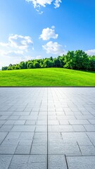 Empty paved plaza, leading to a lush green landscape under a clear blue sky