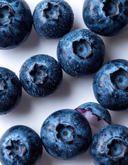 Close-up of fresh blueberries, some whole, others halved, arranged in a loose, circular pattern on a white background. 