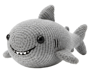 a gray shark toy with a big fin and a wide smiling mouth, made of crochet