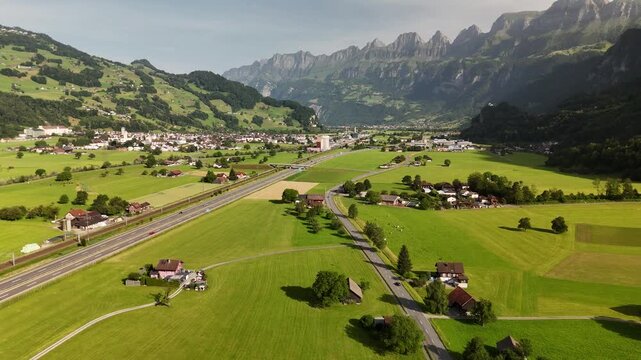 Aerial Drone View of Green Valley with Villages, Roads, and Mountains in the Swiss Alps near Flums and Walenstadt, St. Gallen, Switzerland