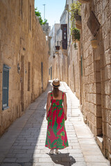 Naklejka premium Mdina, City of Silence, Malta. Woman in a colorful dress with her back turned.