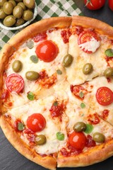 Delicious pizza with cheese, tomatoes and olives on black table, flat lay