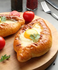 Tasty khachapuris with cheese and eggs served on grey table, closeup