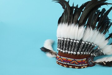 Traditional warbonnet (Native American chief headdress) on light blue background, space for text